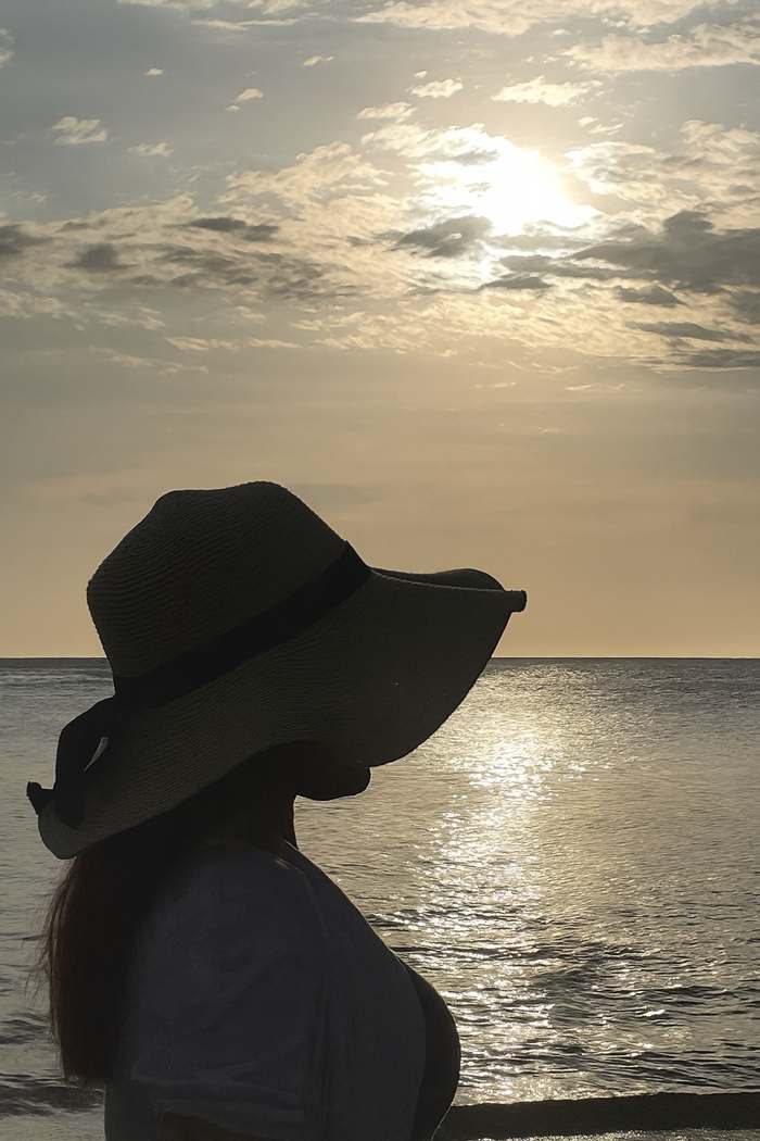 Arlenys en silueta, mirando el mar al atardecer